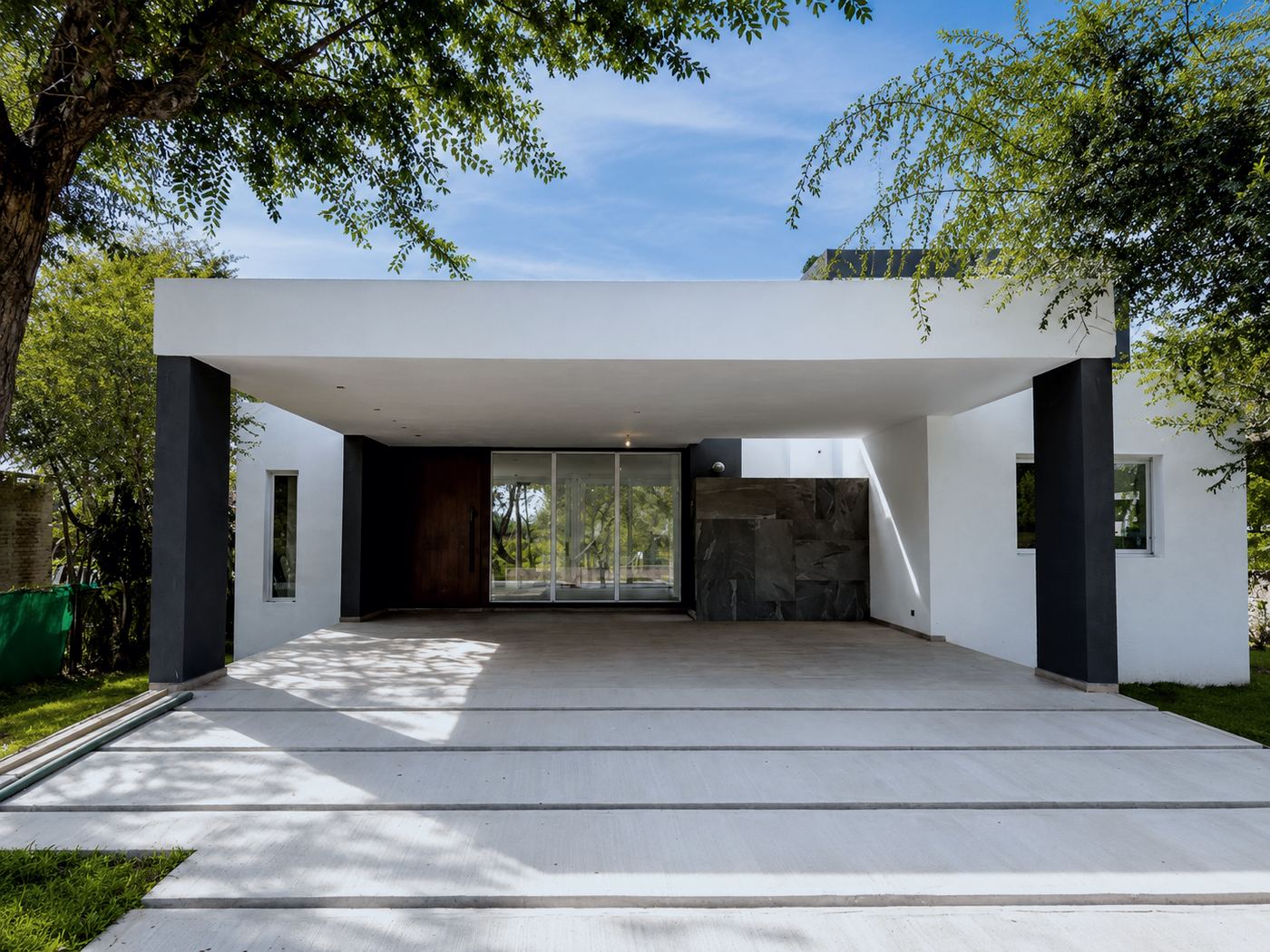 Galería y cochera cubiertas entre árboles