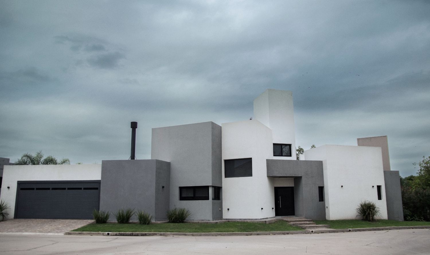 Casa de volúmenes blancos y grises bajo cielo nublado